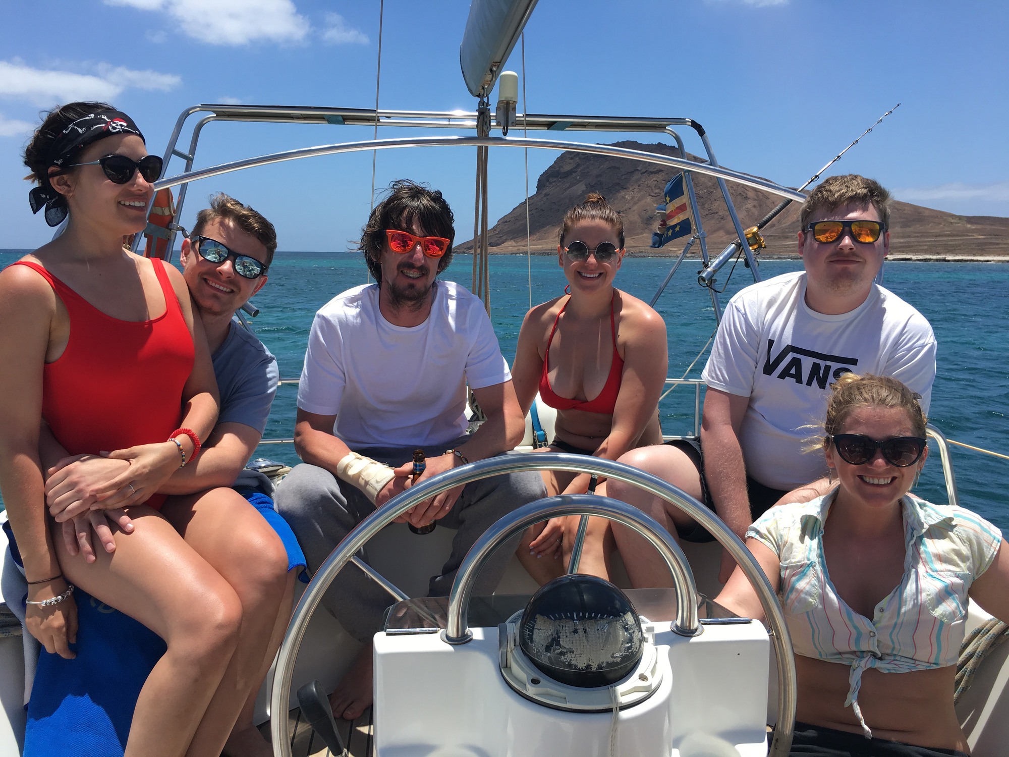 Friends sitting around the steering wheel of the boat