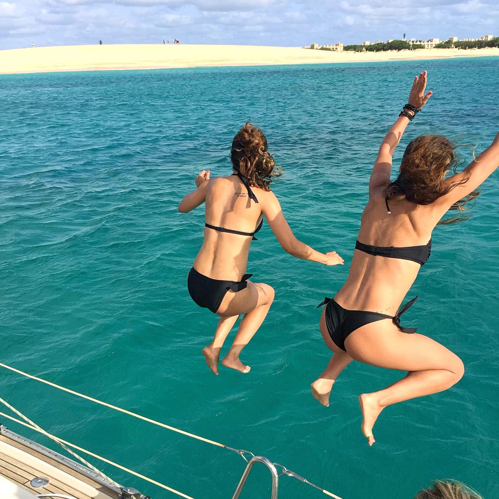 some girls are jumping from the boat during a sailing trip